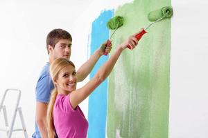 couple heureux peindre un mur dans une nouvelle maison photo