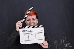 Redhead woman holding clapper sur fond noir photo