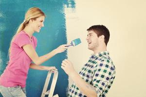 couple heureux peindre un mur dans une nouvelle maison photo