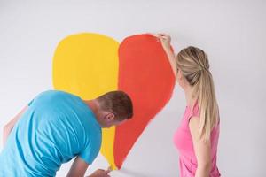 un couple peint un coeur sur le mur photo