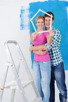 couple heureux peindre un mur dans une nouvelle maison photo