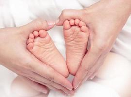 pied de bébé dans les mains de la mère gros plan photo