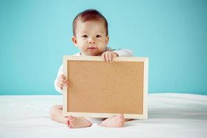 enfant en bas âge tenant une planche vide, prise de vue en studio photo