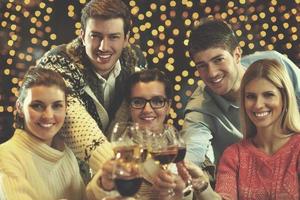 groupe de jeunes gens heureux boivent du vin à la fête photo