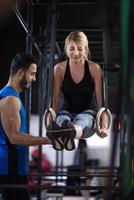 femme travaillant avec un entraîneur personnel sur les anneaux de gymnastique photo