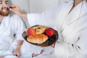 le mec et la fille en peignoir, la fille nourrit le mec de fruits photo