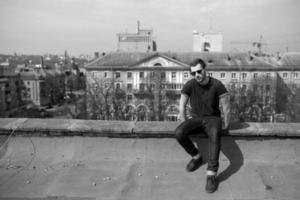 l'homme aux authentiques bottes et jeans lisière sur le toit de l'immeuble de la vieille ville photo