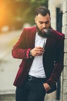 homme riche avec une barbe fume une cigarette électronique photo