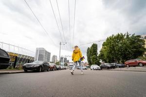 une belle jeune fille tient une planche à roulettes et traverse la route photo