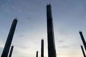 silhouette de colonnes de ciment entourées d'une pellicule plastique pendant le processus de durcissement. sous le ciel du soir. photo