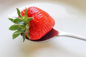 fraises avec des feuilles sur une assiette dans un bol en verre. isolé sur fond blanc. photo