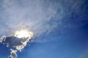belle vue sur les rayons du soleil avec quelques reflets et nuages dans un ciel bleu photo