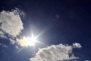 belle vue sur les rayons du soleil avec quelques reflets et nuages dans un ciel bleu photo