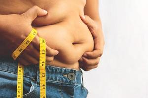 Fat man check out corps surpoids abdomen son ventre avec ruban à mesurer à la main photo