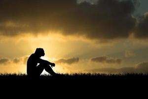 le concept de désespoir, de découragement et de solitude. silhouettes de personnes assises la tête baissée dans le chagrin dans les prés. photo