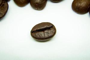 la façon dont les grains de café reposent sur un fond blanc, des grains de café élégants et délicieux et l'arôme du café du matin. photo