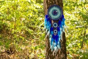 attrape-rêves fait à la main avec des fils de plumes et des cordes de perles suspendues photo