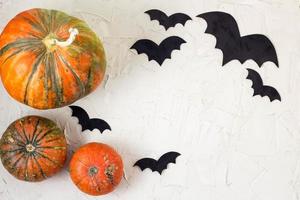 citrouille orange et chauves-souris en papier sur tableau blanc, concept halloween photo