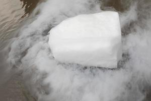 la neige carbonique s'évapore dans l'eau. vapeur d'un gros morceau de glace. expérience chimique. photo