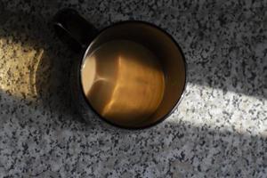 une tasse de café sur la table. boire le matin. tasse en verre noir. photo