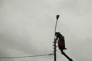 le gratte-ciel change les fils. travailler en hauteur. réparation d'un poteau avec une lampe. photo