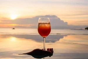 un cocktail dans le verre à vin au-dessus de la piscine. belle scène reflet de l'eau. photo