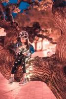 fille d'âge préscolaire assise sur une branche d'arbre photo