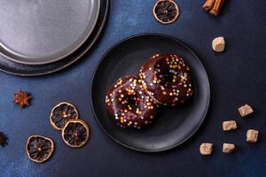 notion de pâtisseries. beignets au glaçage au chocolat avec pépites, sur une table en béton foncé photo