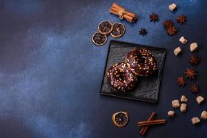 notion de pâtisseries. beignets au glaçage au chocolat avec pépites, sur une table en béton foncé photo
