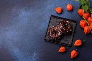 notion de pâtisseries. beignets au glaçage au chocolat avec pépites, sur une table en béton foncé photo