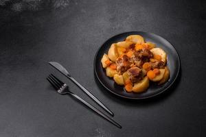 ragoût de viande de boeuf et de légumes sur une plaque noire avec pommes de terre rôties photo
