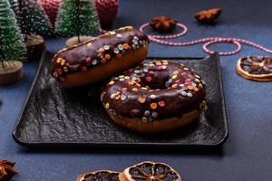 notion de pâtisseries. beignets au glaçage au chocolat avec pépites, sur une table en béton foncé photo