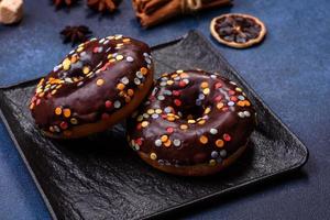 notion de pâtisseries. beignets au glaçage au chocolat avec pépites, sur une table en béton foncé photo