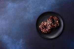 notion de pâtisseries. beignets au glaçage au chocolat avec pépites, sur une table en béton foncé photo