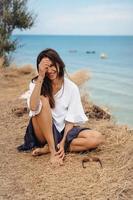 jolie femme en jupe et chemise d'été est assise sur le rivage photo