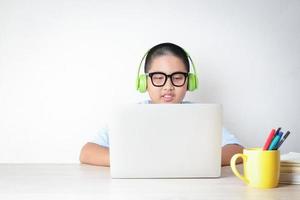 les étudiants masculins asiatiques apprennent en ligne depuis chez eux par le biais d'appels vidéo, en utilisant leurs ordinateurs portables pour communiquer avec leurs professeurs. distance sociale pour réduire la propagation du coronavirus.