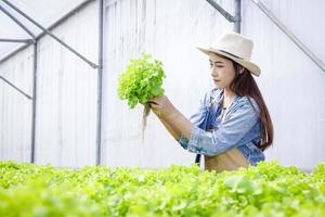 belle femme asiatique faire de l'agriculture, cultiver des légumes à salade dans des serres avec des systèmes hydroponiques. nouvelle agriculture, cultiver des légumes sans sol. concept d'entreprise d'aliments biologiques. copie espace