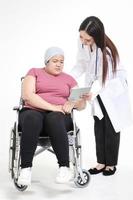 belle femme médecin guérit les maux des patientes obèses asiatiques assises sur un fauteuil roulant. l'obésité est un problème de santé pour le corps. traitement du cancer. espace de copie. fond blanc photo