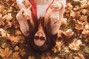 vue de dessus de la belle jeune femme se trouve sur les feuilles d'automne photo