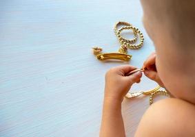 les mains des enfants jouent avec des bijoux en or et de la bijouterie, sur fond blanc. concept de bonheur féminin photo