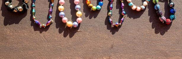 tas de perles de bijoux lumineuses colorées sur fond sombre. collier de perles de pierres précieuses différentes. bijou collier mode moderne motif ou texture. espace de copie. photo