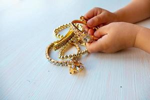 les mains des enfants jouent avec des bijoux en or et de la bijouterie, sur fond blanc. concept de bonheur féminin photo