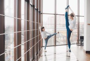 mère apprenant à sa fille à faire un étirement de la jambe haute photo