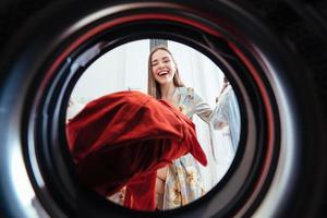 jeune femme à la maison met la robe dans la machine à sécher. photo