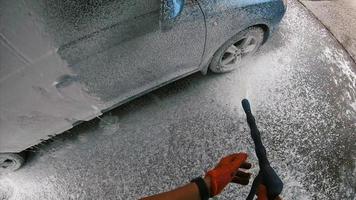 jeune homme couvert de mousse de savon sur sa voiture photo