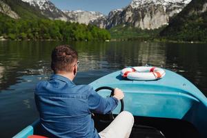 beau jeune homme contrôle un bateau à moteur sur un lac de montagne photo