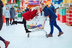 jeune beau mec monte une fille dans un supermarché dans un chariot photo