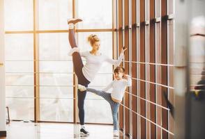 mère apprenant à sa fille à faire un étirement de la jambe haute photo