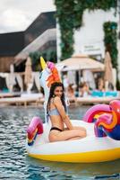 femme sur matelas gonflable licorne flotteur dans la piscine. photo