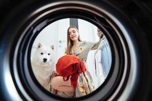 jeune femme à la maison met la robe dans la machine à sécher. photo